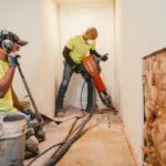 Zander employee with jackhammer digging out drain tile site
