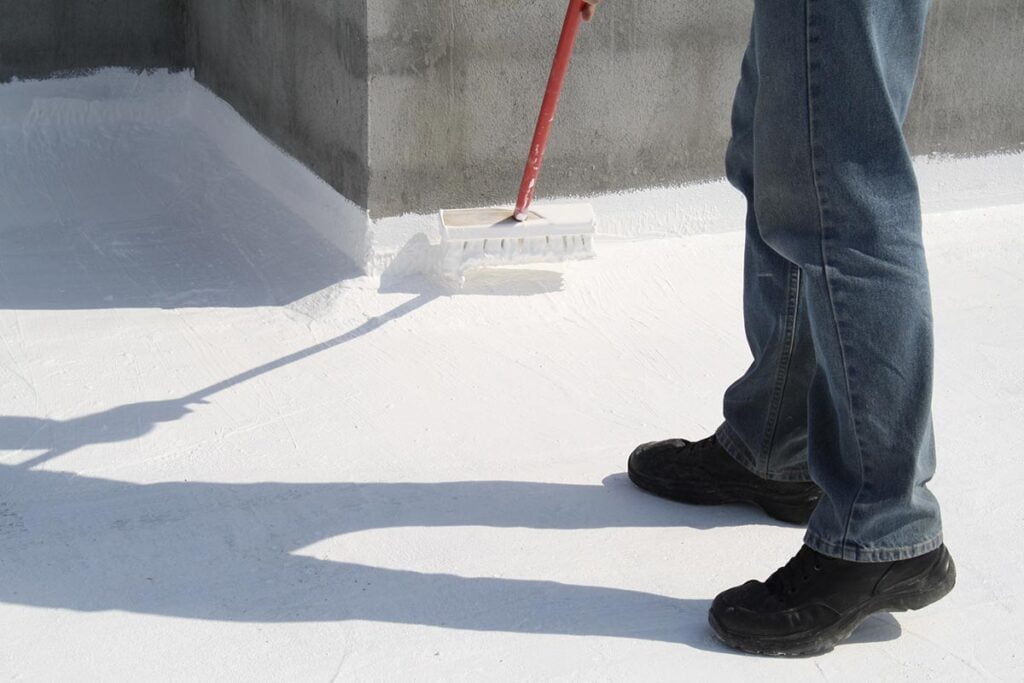 worker applying coatings to a roof