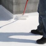 worker applying coatings to a roof