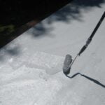 worker applying coatings to a roof