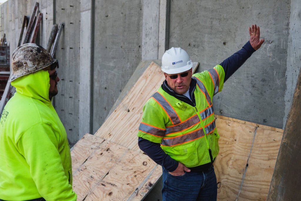 Zander employee gesturing toward a wall while talking with another employee