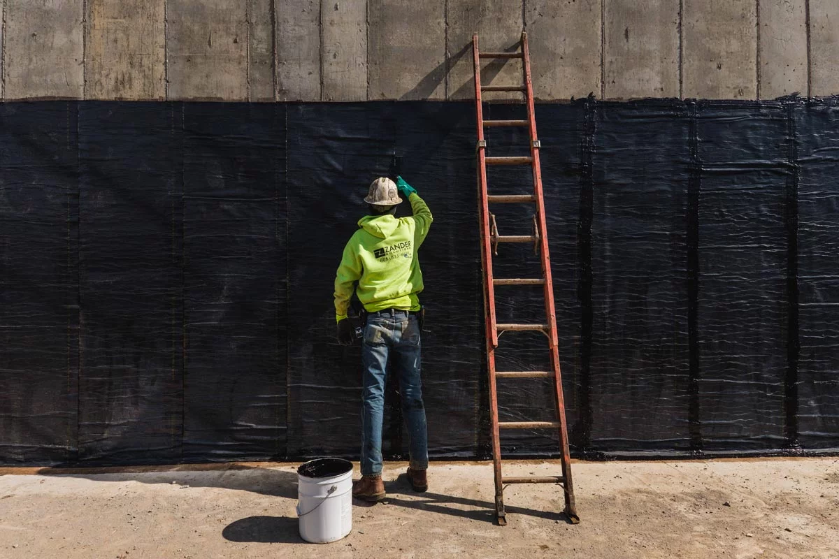 Zander employee applying waterproofing to wall