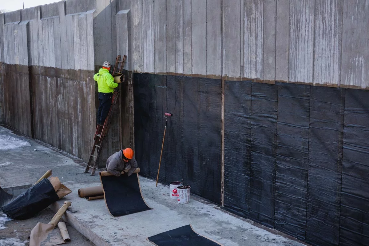 Zander employees applying waterproofing to wall