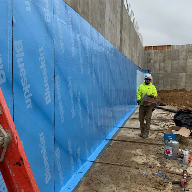Zander employee walking along a wall at a commercial foundation waterproofing job site