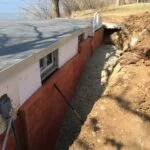 a trench dug out around a wall with panels place in-between
