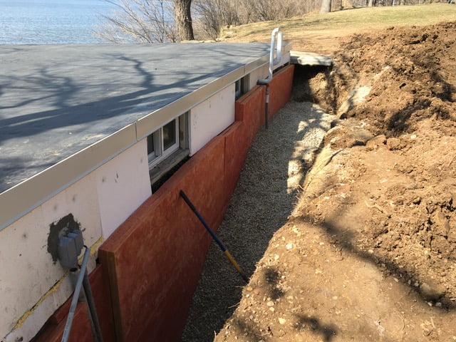a trench dug out around a wall with panels place in-between