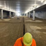 an employee standing near a trench dug out for radon mediation piping