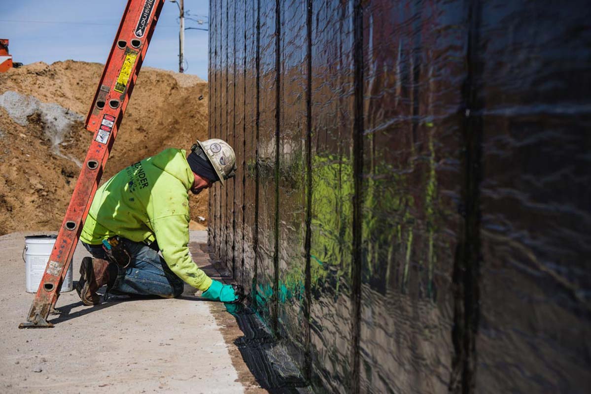 Zander employee applying water proofing to a wall
