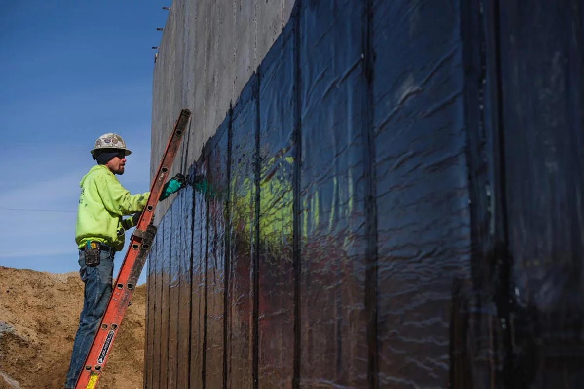 Zander employee applying water proofing to a wall