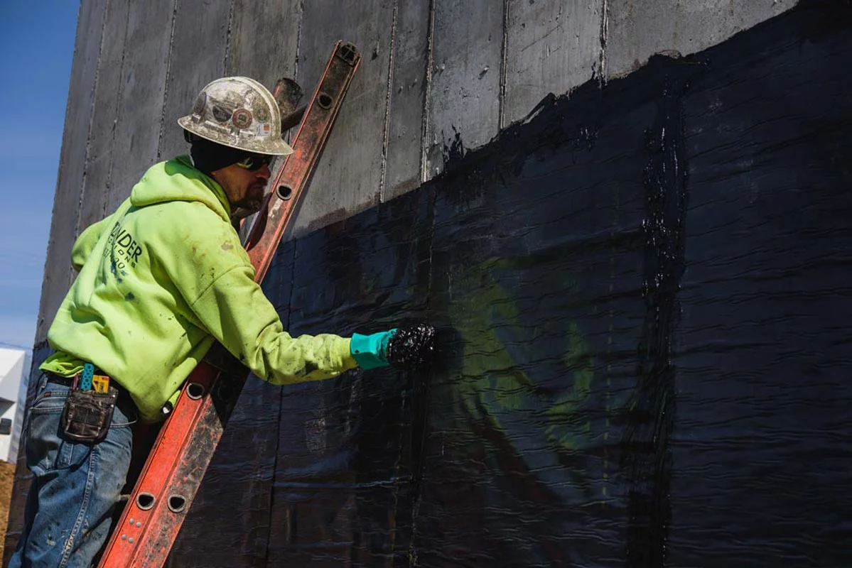 Zander employee applying water proofing to a wall