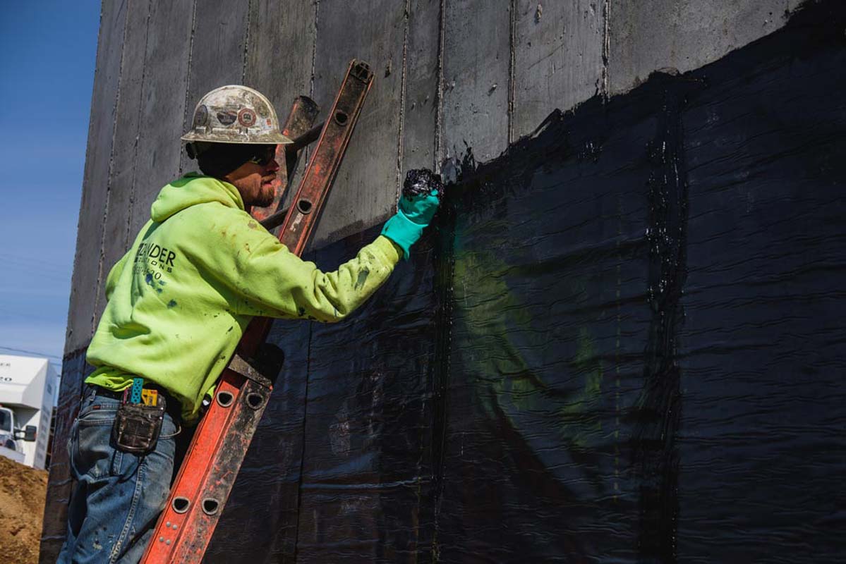 Zander employee applying water proofing to a wall