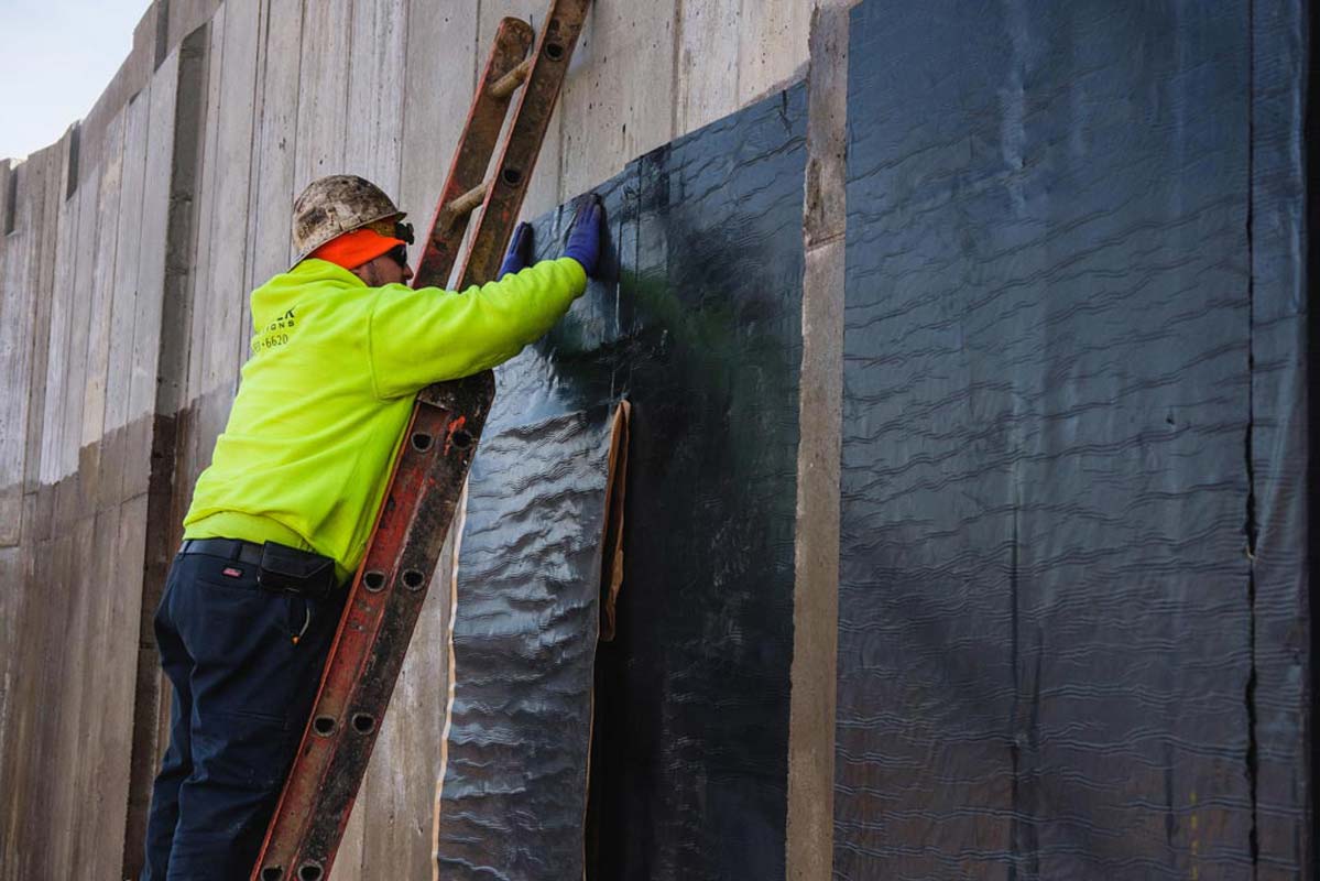 Zander employee applying water proofing to a wall