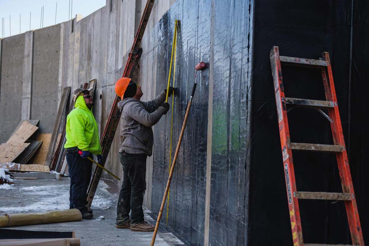 Zander employees applying water proofing to a wall