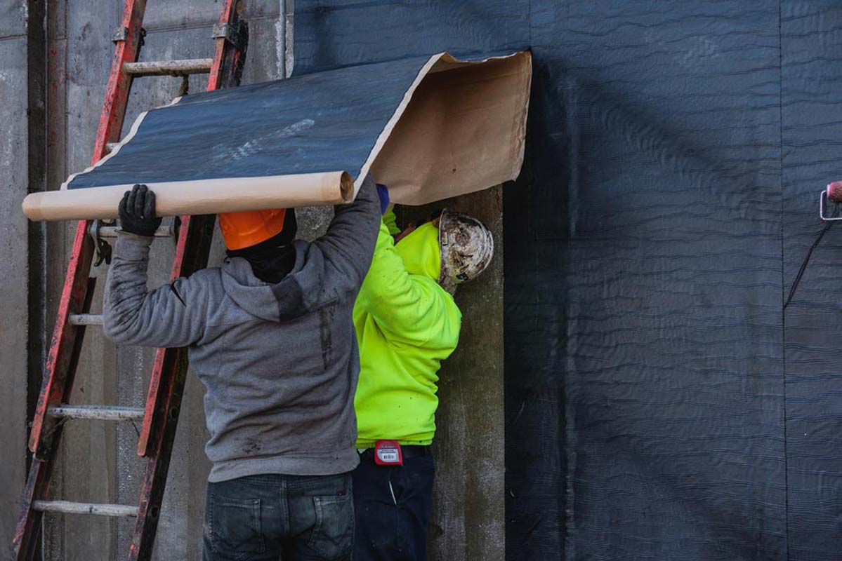 Zander employees applying water proofing to a wall