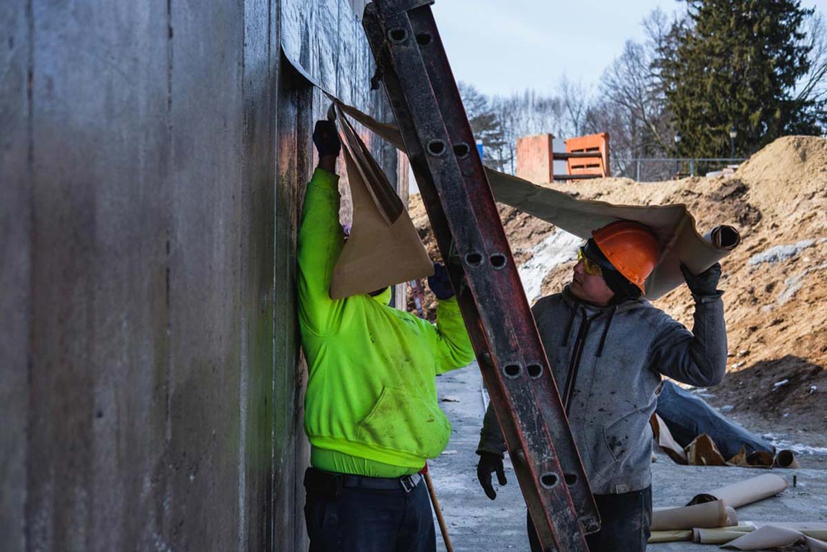 Zander employees applying water proofing to a wall