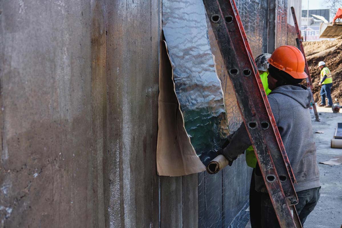 Zander employees applying water proofing to a wall