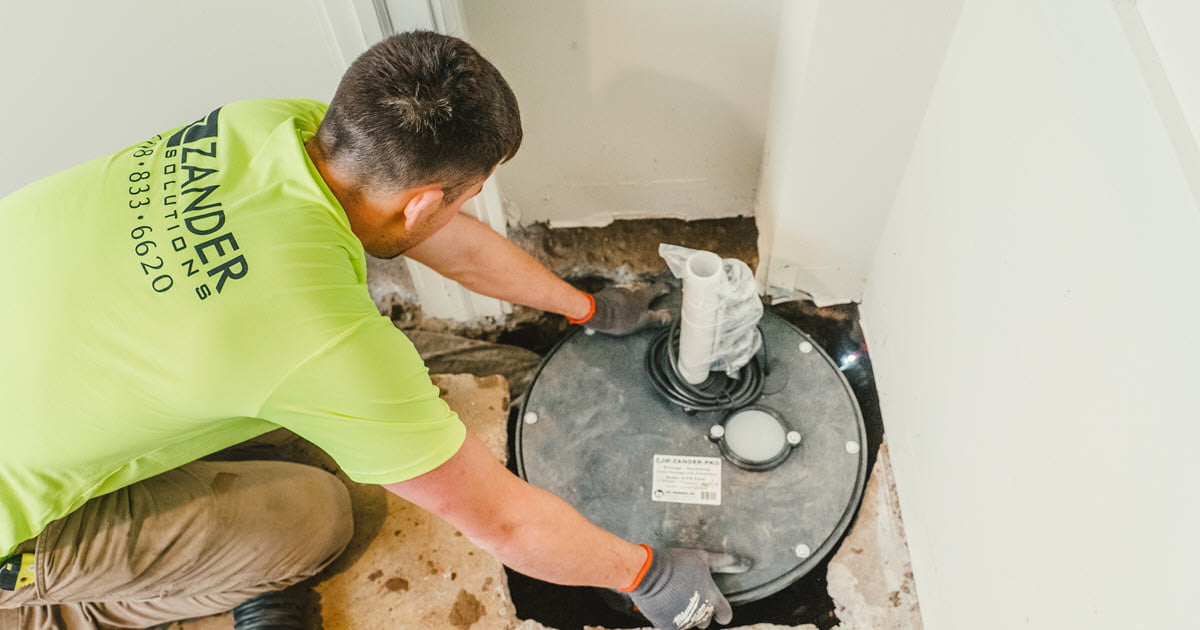 Zander employee installing a sump pump